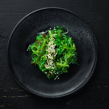 Siyah tabakta yosun salatası. Chuka Wakame eski arkaplanda. Üst Manzara. Metnin için boş yer.