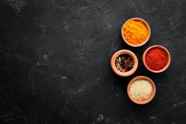 Siyah taş arka planda renkli baharatlar. Metniniz için boş alan. Üst görünüm.