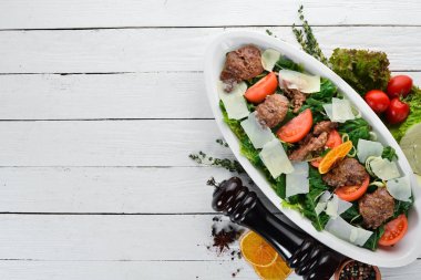 Kaz karaciğeri, ıspanak, domates ve parmesan peyniri ile salata. Ahşap bir arka planda. Üst görünüm. Ücretsiz kopya alanı