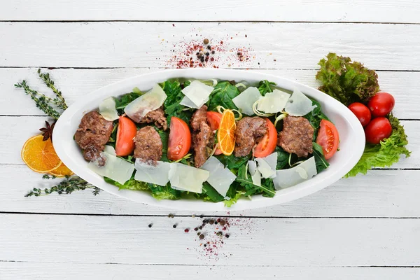 Kaz karaciğeri, ıspanak, domates ve parmesan peyniri ile salata. Ahşap bir arka planda. Üst görünüm. Ücretsiz kopya alanı