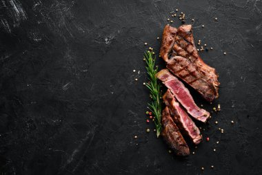 Veal steak on a bone on a black background. Free space for your text. Top view. clipart