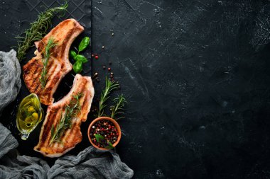 Biberiye ile kemik üzerinde biftekler. Mangal, Barbekü. Siyah taş arka planda. Üst görünüm. Ücretsiz kopya alanı.