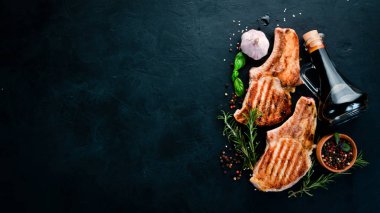 Biberiye ile kemik üzerinde biftekler. Mangal, Barbekü. Siyah taş arka planda. Üst görünüm. Ücretsiz kopya alanı.