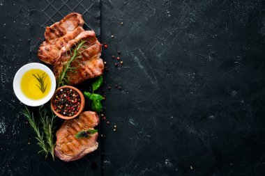 Biberiye ile kemik üzerinde biftekler. Mangal, Barbekü. Siyah taş arka planda. Üst görünüm. Ücretsiz kopya alanı.