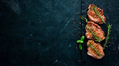 Biberiye ile kemik üzerinde biftekler. Mangal, Barbekü. Siyah taş arka planda. Üst görünüm. Ücretsiz kopya alanı.