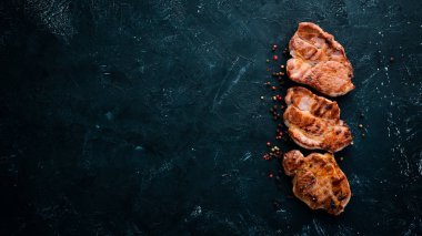 Biberiye ile kemik üzerinde biftekler. Mangal, Barbekü. Siyah taş arka planda. Üst görünüm. Ücretsiz kopya alanı.