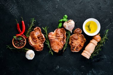 Biberiye ile kemik üzerinde biftekler. Mangal, Barbekü. Siyah taş arka planda. Üst görünüm. Ücretsiz kopya alanı.