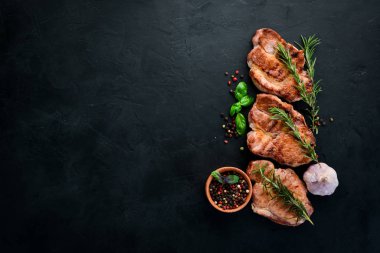 Biberiye ile kemik üzerinde biftekler. Mangal, Barbekü. Siyah taş arka planda. Üst görünüm. Ücretsiz kopya alanı.