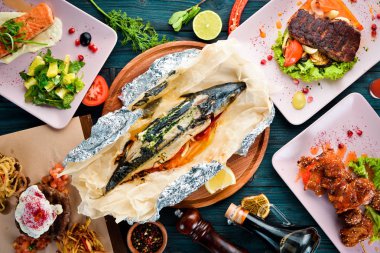 Siyah bir plakada pişmiş sığır eti ve ızgara sebzeler. Ahşap bir arka planda. Üst görünüm. Metniniz için boş alan.