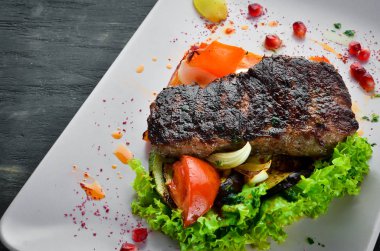 Bir tabak sebze üzerinde dana eti. Ahşap bir arka planda. Üst görünüm. Metniniz için boş alan.