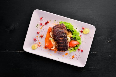 Bir tabak sebze üzerinde dana eti. Ahşap bir arka planda. Üst görünüm. Metniniz için boş alan.