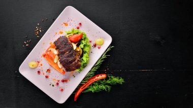 Bir tabak sebze üzerinde dana eti. Ahşap bir arka planda. Üst görünüm. Metniniz için boş alan.