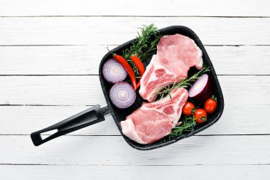 Kemikte çiğ biftek. Baharat ve otlar ile et. Beyaz ahşap bir arka planda. Üst görünüm. Ücretsiz kopya alanı.