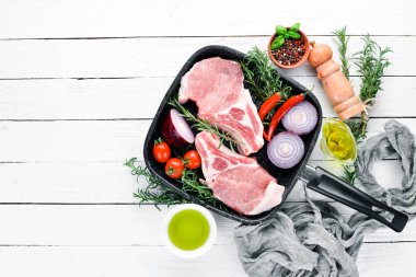 Kemikte çiğ biftek. Baharat ve otlar ile et. Beyaz ahşap bir arka planda. Üst görünüm. Ücretsiz kopya alanı.