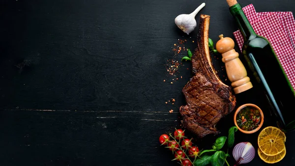 Kemik üzerinde biftek. Tomahawk biftek siyah ahşap arka planda. Üst görünüm. Ücretsiz kopya alanı.