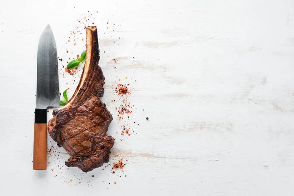 Steak on the bone. tomahawk steak On a black wooden background. Top view. Free copy space.