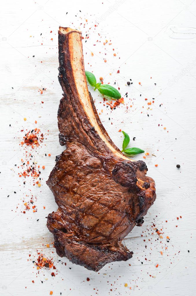 Steak on the bone. tomahawk steak On a black wooden background. Top view. Free copy space.