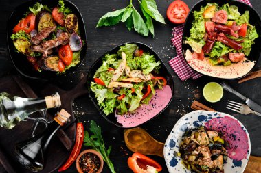 Yemek ve yemeklerin arka planı. Et ve balık yemekleri ve salata. Ahşap bir arka planda. Üst görünüm. Metniniz için boş alan.