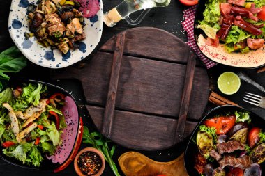 Yemek ve yemeklerin arka planı. Et ve balık yemekleri ve salata. Ahşap bir arka planda. Üst görünüm. Metniniz için boş alan.