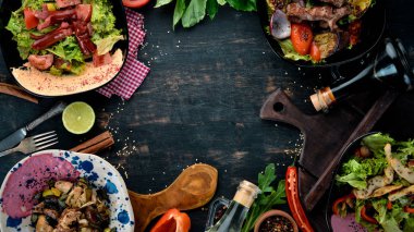 Yemek ve yemeklerin arka planı. Et ve balık yemekleri ve salata. Ahşap bir arka planda. Üst görünüm. Metniniz için boş alan.