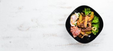 Haşlanmış yumurta ve pastırma ile pişmiş patates. Ahşap bir arka planda. Üst görünüm. Metniniz için boş alan.