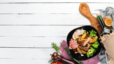 Haşlanmış yumurta ve pastırma ile pişmiş patates. Ahşap bir arka planda. Üst görünüm. Metniniz için boş alan.