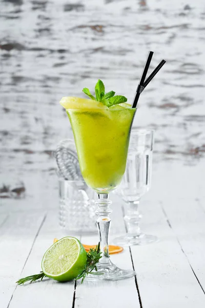 Tropical Green Alcoholic Cocktail. Rum, mint, and pineapple juice. Alcoholic cocktail in a glass. On a wooden background. Top view. Free copy space.