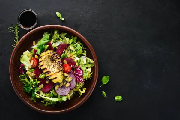 Salata. Marul, pancar, avokado ve Kabak tohumları. Üst görünüm. Siyah bir arka planda. Ücretsiz kopya alanı.