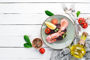 Karides ve sebzeler ile siyah pirinç. Eski arka planda. Üst görünüm. Metniniz için boş alan.