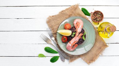 Karides ve sebzeler ile siyah pirinç. Eski arka planda. Üst görünüm. Metniniz için boş alan.