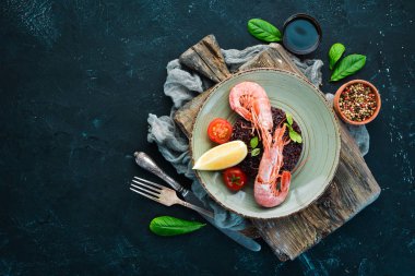 Karides ve sebzeler ile siyah pirinç. Eski arka planda. Üst görünüm. Metniniz için boş alan.