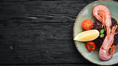 Karides ve sebzeler ile siyah pirinç. Eski arka planda. Üst görünüm. Metniniz için boş alan.