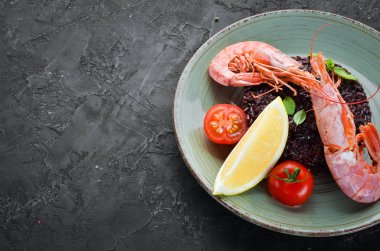 Karides ve sebzeler ile siyah pirinç. Eski arka planda. Üst görünüm. Metniniz için boş alan.