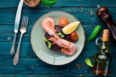 Karides ve sebzeler ile siyah pirinç. Eski arka planda. Üst görünüm. Metniniz için boş alan.