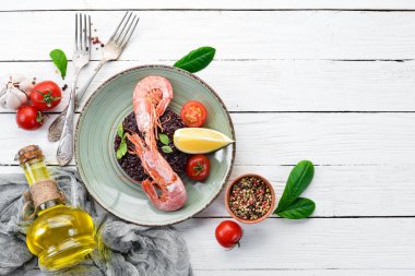 Karides ve sebzeler ile siyah pirinç. Eski arka planda. Üst görünüm. Metniniz için boş alan.