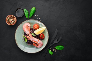 Karides ve sebzeler ile siyah pirinç. Eski arka planda. Üst görünüm. Metniniz için boş alan.