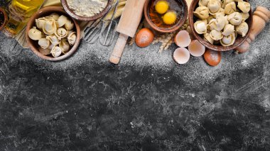 Ev yapımı ravioli. Köfte. Un, yumurta, siyah bir arka planda hamur. Üst görünüm. Ücretsiz kopya alanı