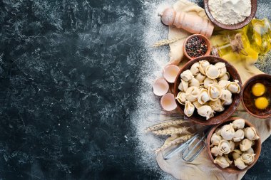 Ev yapımı ravioli. Köfte. Un, yumurta, siyah bir arka planda hamur. Üst görünüm. Ücretsiz kopya alanı