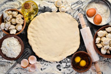 Ev yapımı ravioli. Köfte. Un, yumurta, siyah bir arka planda hamur. Üst görünüm. Ücretsiz kopya alanı