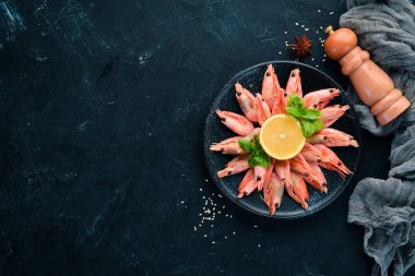 Siyah bir arka planda bir plaka içinde limon ile karides. Üst görünüm. Ücretsiz kopya alanı.