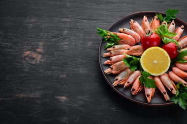 Siyah bir arka planda bir plaka içinde limon ile karides. Üst görünüm. Ücretsiz kopya alanı.