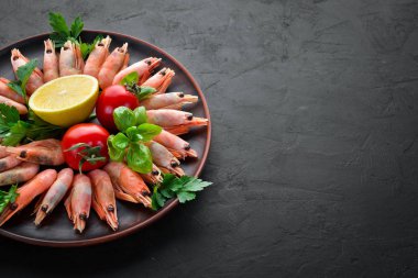 Siyah bir arka planda bir plaka içinde limon ile karides. Üst görünüm. Ücretsiz kopya alanı.