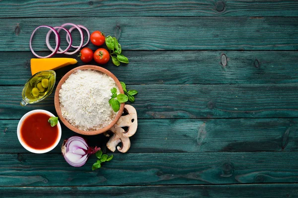 Pizza yapmak için malzemeler. Ahşap bir arka planda. Üst görünüm. Metniniz için boş alan.