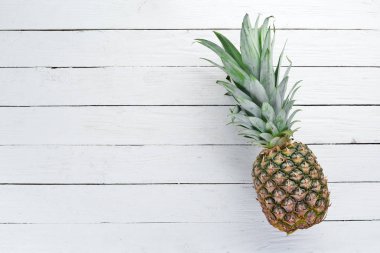 Beyaz ahşap arka planda ananas. Tropikal meyveler. Üst görünüm. Ücretsiz kopya alanı.