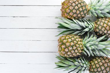 Beyaz ahşap arka planda ananas. Tropikal meyveler. Üst görünüm. Ücretsiz kopya alanı.