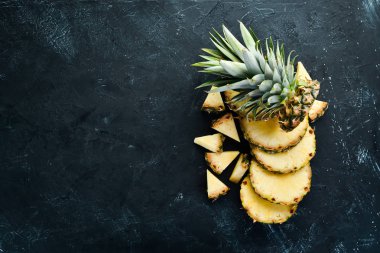 Siyah bir arka planda dilimlenmiş ananas. Tropikal meyveler. Üst görünüm. Ücretsiz kopya alanı.
