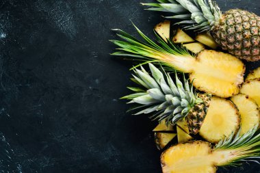 Siyah bir arka planda dilimlenmiş ananas. Tropikal meyveler. Üst görünüm. Ücretsiz kopya alanı.