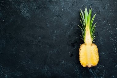 Siyah bir arka planda dilimlenmiş ananas. Tropikal meyveler. Üst görünüm. Ücretsiz kopya alanı.