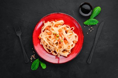 Bir tabak içinde sebze ve domates sosu ile makarna. Eski arka planda. Üst görünüm. Metniniz için boş alan.