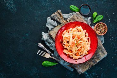 Bir tabak içinde sebze ve domates sosu ile makarna. Eski arka planda. Üst görünüm. Metniniz için boş alan.